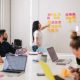 A woman presenting an understanding of knowledge management software to her team using sticky notes.