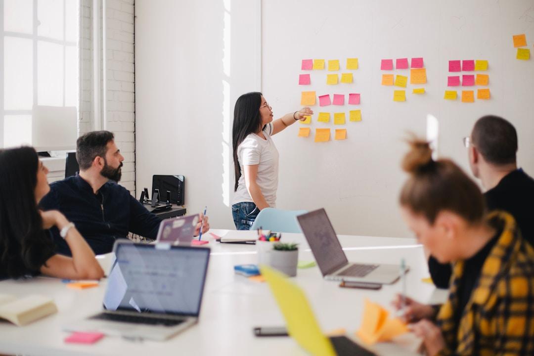 A woman presenting an understanding of knowledge management software to her team using sticky notes.